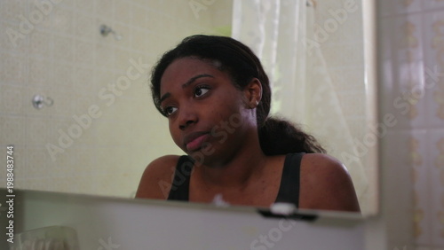 Картината върху платно African American woman gazing into bathroom mirror with pensive expression refle