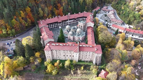 High-angle drone shot of Rila Monastery showing the full complex and surrounding forest.