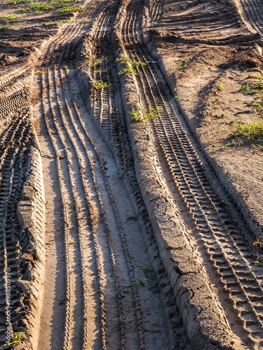 Deep tracks of heavy machinery across a sandy lot, construction site of a future house in a suburban residential development on a sunny morning in southwest Florida. Motifs of work and transformation.