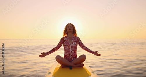 A happy young woman walking on a sup board by the sea during her summer vacation. Slow motion