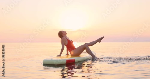 A happy young woman walking on a sup board by the sea during her summer vacation. Slow motion