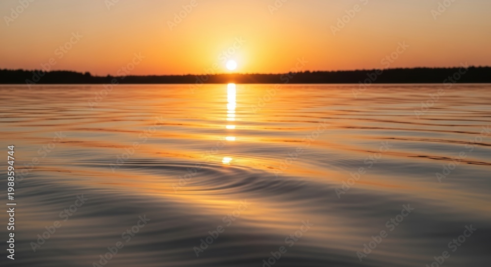 Obraz premium Sunset over calm water with ripples on the surface reflecting the vibrant orange sky