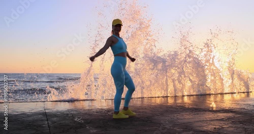 Fit woman showing muscles at the beach during summer vacation. Slow motion