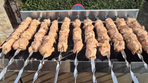 The kebabs are grilled on the coals while rotating.