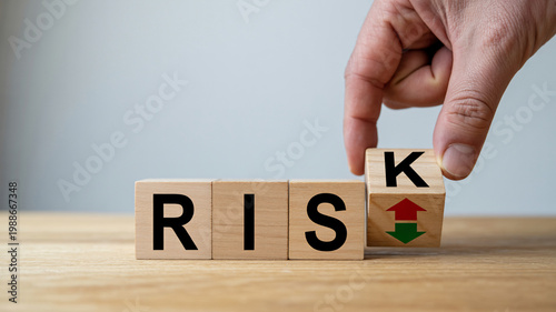 A hand flipping a wooden block to increase risk