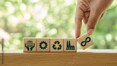 A hand placing a wooden block with an infinity symbol on a row of blocks representing sustainability and eco-friendliness