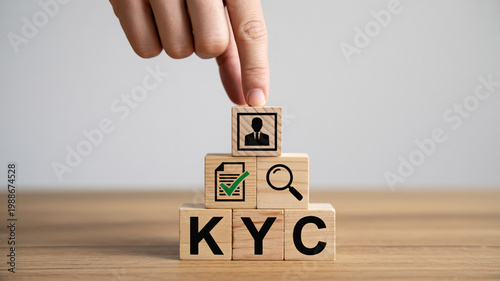 A hand stacking wooden blocks with KYC and verification icons on a wooden surface