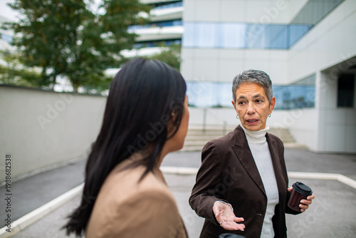 Two businesswomen discussing work outside office building