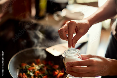 Konstfotografi Home cook seasoning vegetables with salt in kitchen