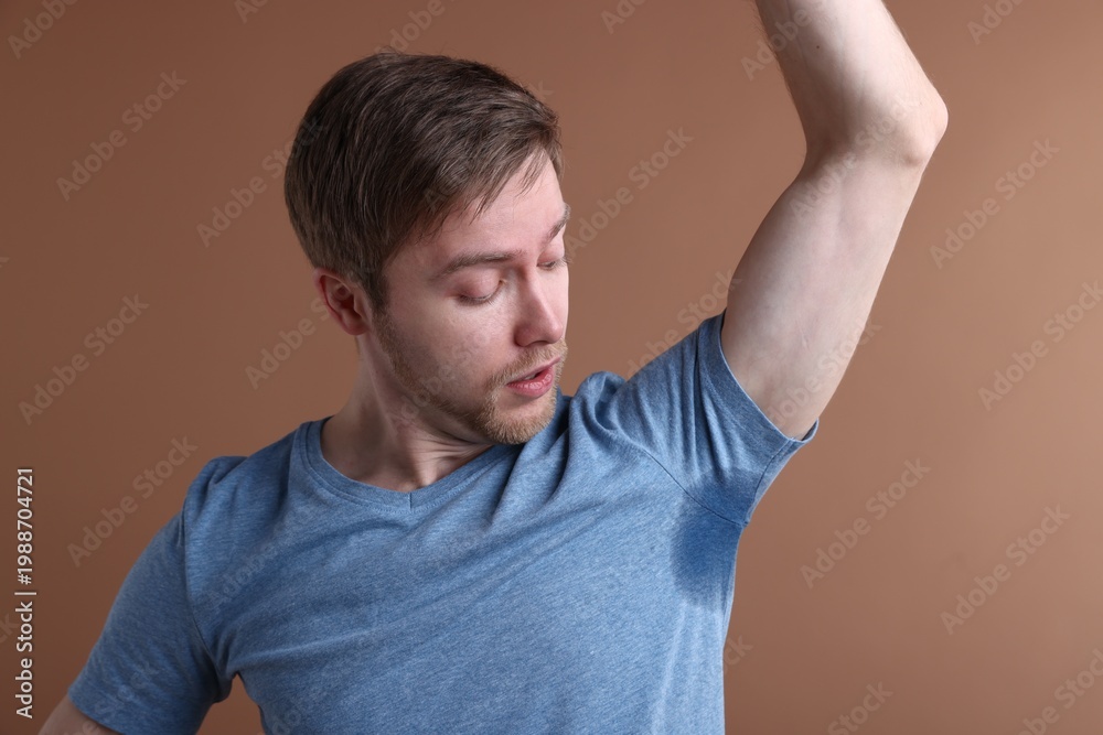 Obraz premium Man with sweaty armpits on brown background