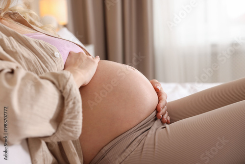 Φωτογραφία Beautiful pregnant woman touching her belly on bed at home, closeup