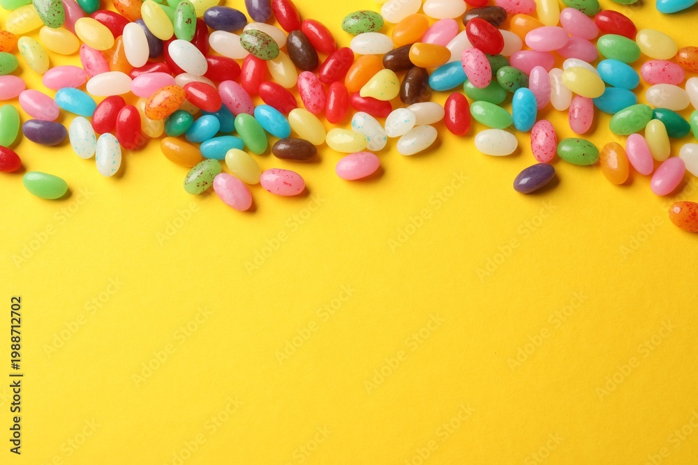 Obraz premium Delicious colorful candies on yellow background, top view. Space for text