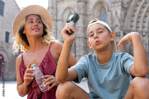 Fotografía Family tourists combating summer heat in the Gothic Quarter, staying cool with a