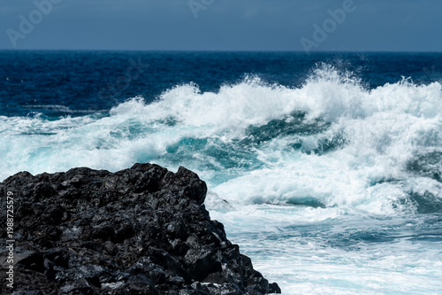Turquoise ocean waves crashing on volcanic rocks coastline in Tenerife Canary Islands Spain, powerful Atlantic sea, blue water motion, dramatic seascape, summer travel destination, natural energy
