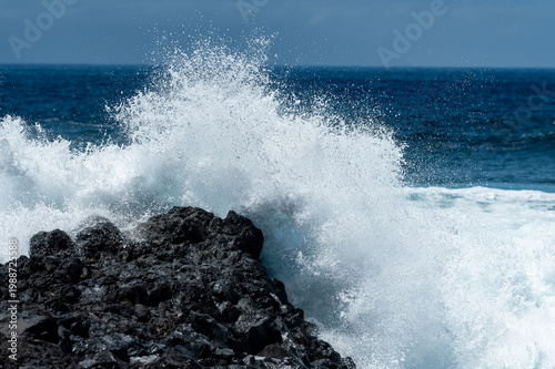 Turquoise ocean waves crashing on volcanic rocks coastline in Tenerife Canary Islands Spain, powerful Atlantic sea, blue water motion, dramatic seascape, summer travel destination, natural energy