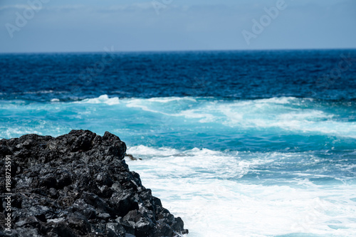 Turquoise ocean waves crashing on volcanic rocks coastline in Tenerife Canary Islands Spain, powerful Atlantic sea, blue water motion, dramatic seascape, summer travel destination, natural energy
