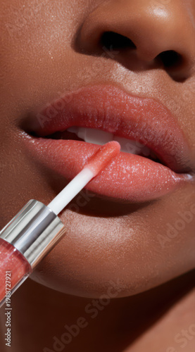 A close-up view shows lips with lip gloss being applied