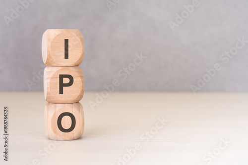 IPO - Initial Public Offering - acronym on vertically stacked wooden blocks. Minimalist financial concept.