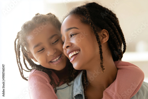 Portrait of happy African American mother and daughter hugging and laughing together, family love concept