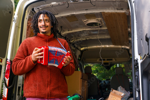 Man holding an accordion standing by moving van