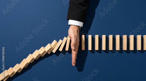 A hand poised to topple a row of wooden dominoes in a business setting