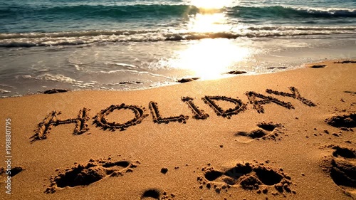 Word HOLIDAY written in sand on beach at sunset