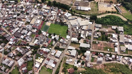 Aerial drone view of Alfredo Chaves city in Espírito Santo, Brazil. Urban area surrounded by green mountains, hills and rural landscape under blue sky, typical countryside scenery.
