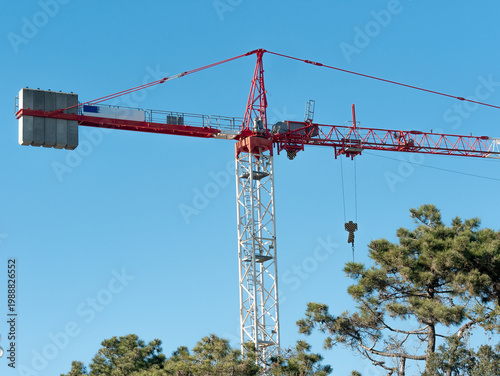 Red and white tower construction crane against a clear sky