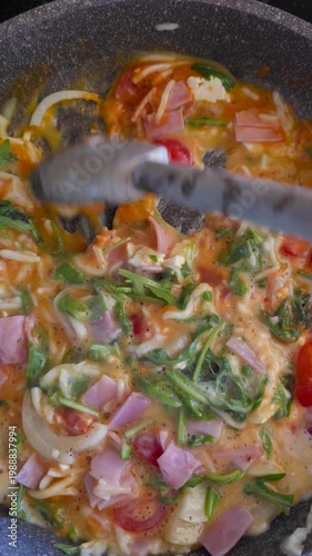 POV cooking scrambled eggs with ham tomato and herbs showing low carb meal for diabetes diet management