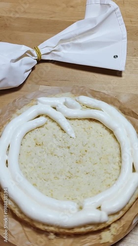 Cake rotating on a stand while a baker spreads cream frosting. Close-up of decorating process, smooth icing, professional or home pastry work, dessert preparation, bakery concept, sweet food video