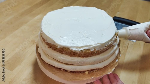 Cake rotating on a stand while a baker spreads cream frosting. Close-up of decorating process, smooth icing, professional or home pastry work, dessert preparation, bakery concept, sweet food video