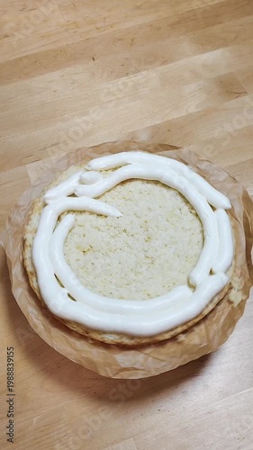 Cake rotating on a stand while a baker spreads cream frosting. Close-up of decorating process, smooth icing, professional or home pastry work, dessert preparation, bakery concept, sweet food video