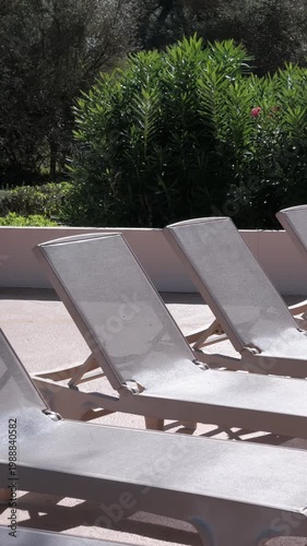 PORTOCOLOM, MALLORCA, SPAIN - OCTOBER, 2025: Bright midday sun shines on empty sun loungers and umbrellas in Portocolom, creating strong contrast and shadows.