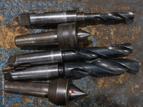 Assorted metal drill bits and live centers on industrial workbench