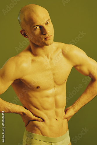 Focused man posing with confidence, showcasing a toned physique. The image features a subtle yellow-green background, emphasizing strength and determination.
