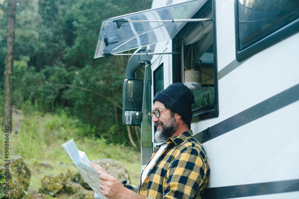 Fototapeta premium Man reading a map beside his camper van during a relaxed forest road trip