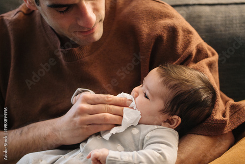 Parent wiping baby's mouth cleaning at home