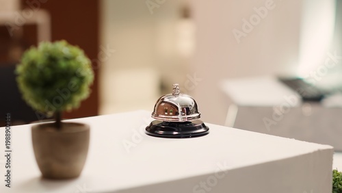 Fotografie Close up of service bell next to mini plant on warm hospitality industry hotel lobby check in desk