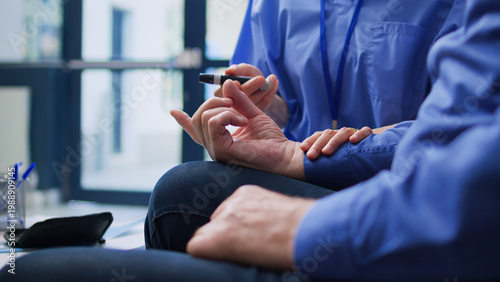 Schilderij op canvas Assistant measuring insulin level and glucose in blood sample using medical glucometer during examination with senior patient with diabetes