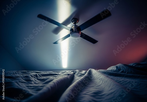 Low angle view of a rotating ceiling fan in a dimly lit bedroom, focusing on shadows and textured linens during a sleepless night scene, late, monochromatic, dark