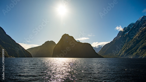 Quadro su tela Silhouettes des pics de Milford Sound en contre-jour avec soleil éblouissant et