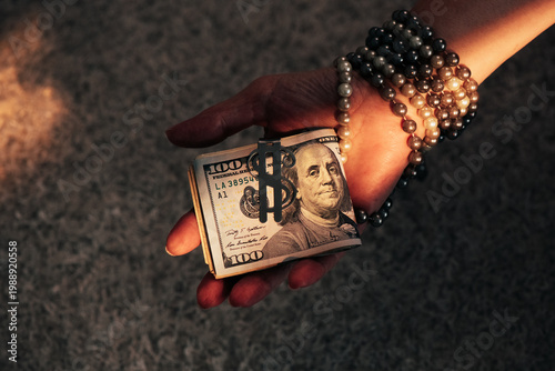 Hand Holding Roll of Hundred Dollar Bills with Money Clip