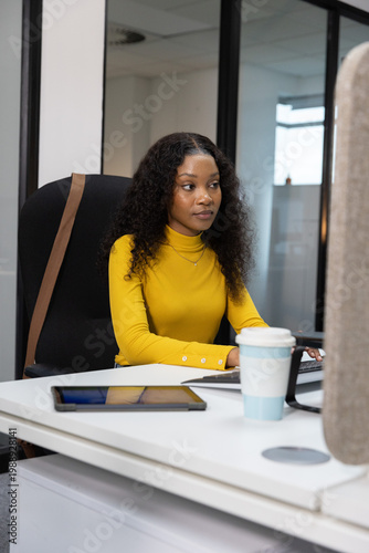 Workstation is showing keyboard, tablet, travel cup, monitor and high-back chair near window