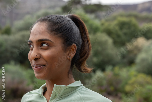 Bild auf Leinwand Indian woman standing on trail in nature reserve, wearing light green zip-up top