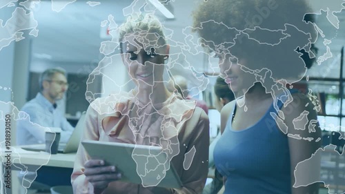 Two women reviewing tablet in office scrolling and causing soft world map overlay for marketing
