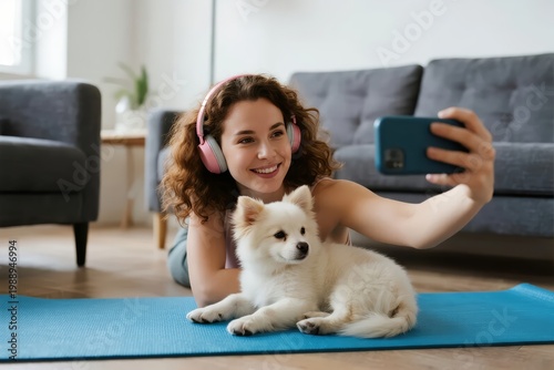 Woman taking selfie with white dog on yoga mat at home