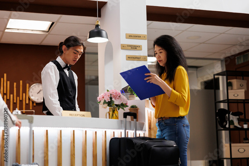 Tableau sur toile Asian guest signs registration form to stay at lavish and modern resort for holiday