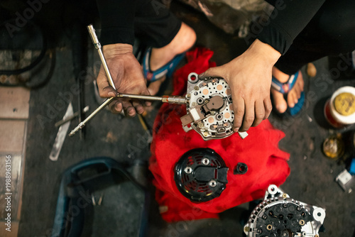 Mechanic inspecting and repairing vehicle alternator using a wrench