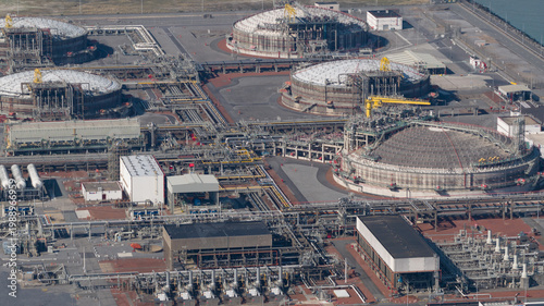 Aerial view of Fluxys - LNG Terminal Zeebrugge with large domed storage tanks, intricate industrial piping, and support buildings in Brugge, Vlaanderen, Belgium.