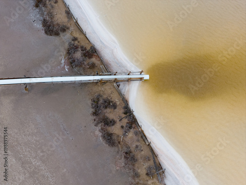 Salt water flowing from a supply pipe into a colorful settling pond 